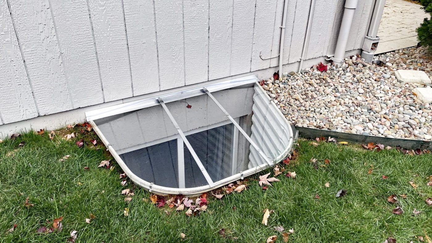 53x37 sloped window well cover surrounded by grass and decorative rocks